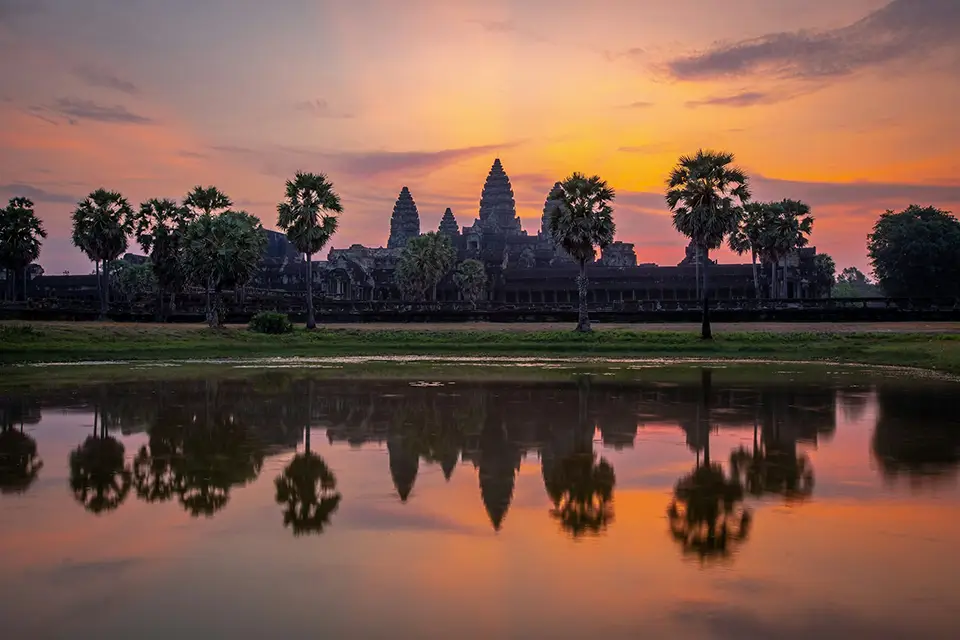 Temple d’Angkor Wat au lever du soleil, avec ses tours emblématiques reflétées dans un bassin, au Cambodge.