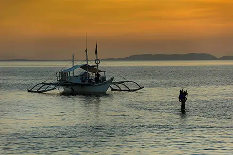 Silhouette d’un bateau à balanciers au coucher du soleil