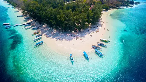 Vue aérienne d’un banc de sable blanc avec bateaux ancrés dans une eau turquoise.