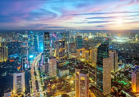 Vue nocturne d’une métropole avec gratte-ciel et routes éclairées.