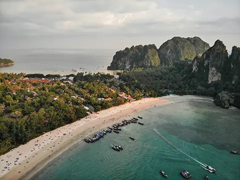 Vue aérienne d’une grande plage courbée avec ville côtière et falaises calcaires.