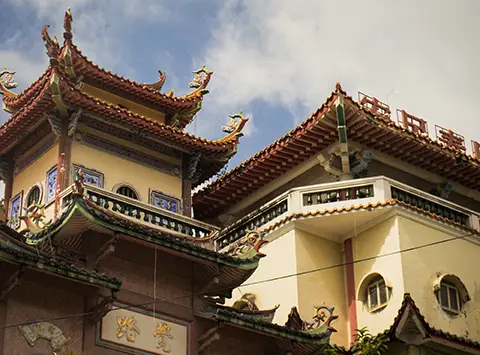 Détails d’un toit de temple asiatique avec ornements colorés et tuiles décorées.