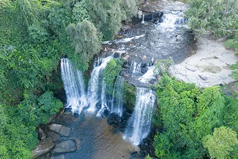 Vue en hauteur d’une cascade à plusieurs niveaux se jetant dans des bassins rocheux.