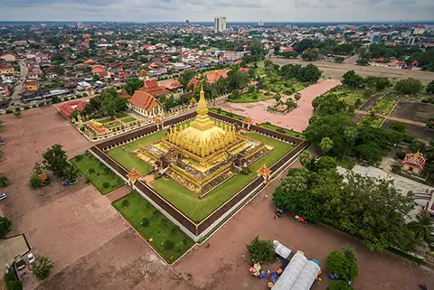 Vue aérienne d’un grand stupa doré et de son complexe entouré de jardins.