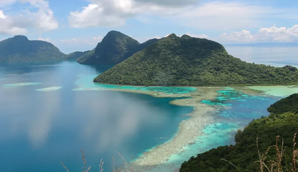 Vue depuis un belvédère sur une lagune bleue et un banc de sable autour d’îles vertes.