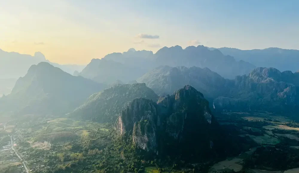 Vue aérienne de montagnes karstiques et vallées dans une lumière douce.